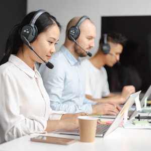 Customer service agents efficiently handle calls using laptops and headsets in a modern office.